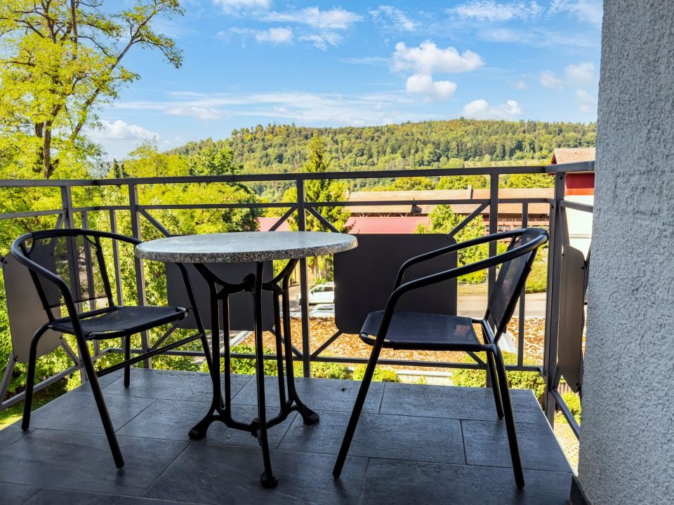 Balkon mit Tisch und zwei Stühlen, Blick auf die bewaldeten Hänge rund um Nagold